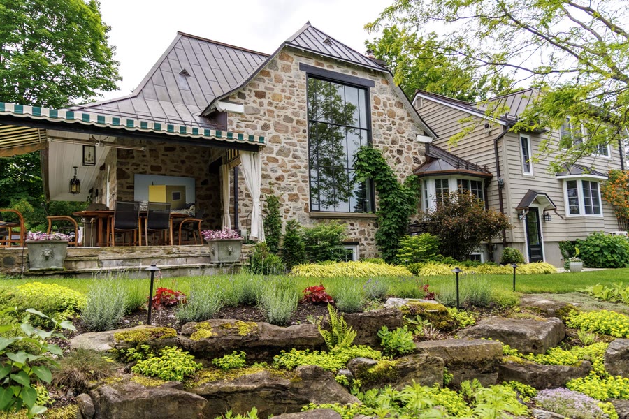 Rocaille fleurie et plates-bandes aménagées devant une maison en pierre